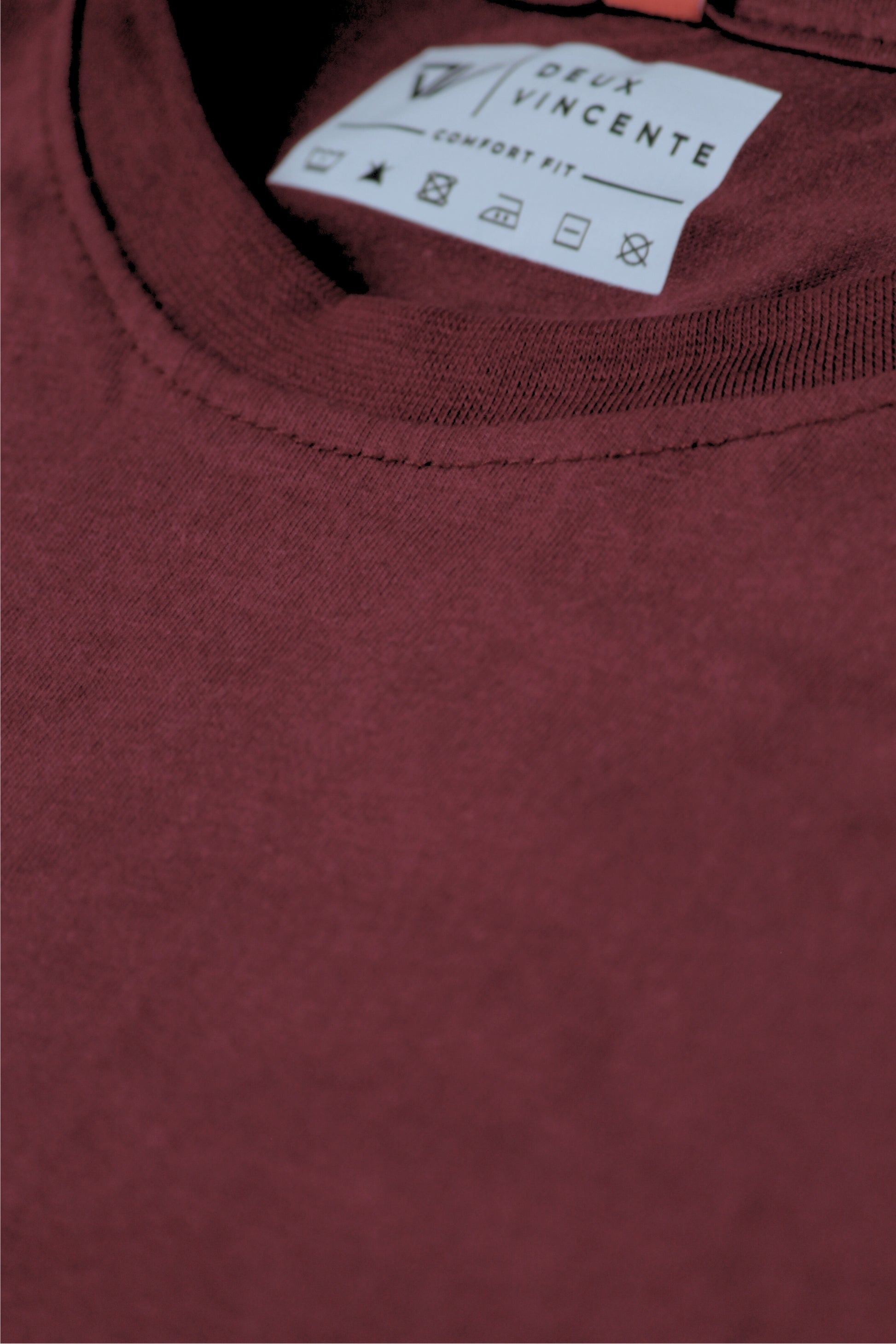 Close-up of a deux vincente maroon t-shirt with a brand label on the collar.